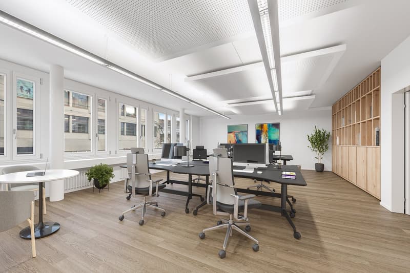 modern office with wooden floors, white walls, large windows, office desks, chairs, monitors, and plants
