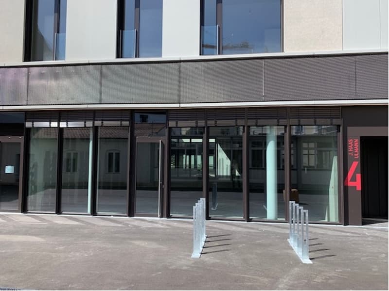 A modern multi-story building with large glass windows and doors, a sleek exterior design, and a prominent entrance with a number 4 displayed.