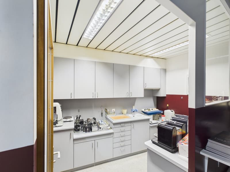 modern kitchen with stainless steel appliances, white cabinets, under cabinet lighting, countertop space, white tiled flooring