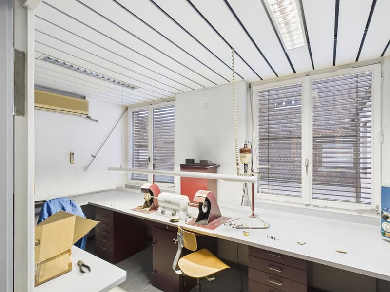 desk with several drawers, tools on the desk, open storage box, chair, large windows