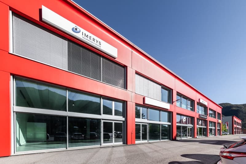 red building, glass doors, wide windows, cars parked in front, mountains in the background