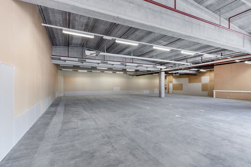 Concrete floor, high ceilings, exposed metal beams, rows of parking spots, overhead lighting