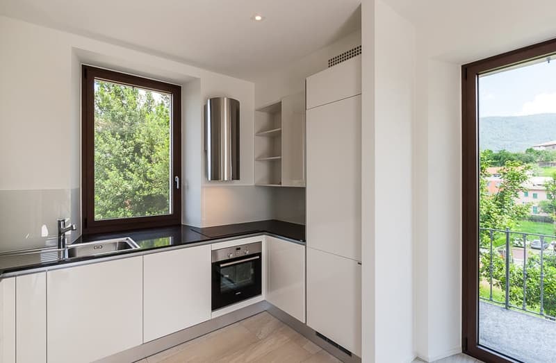 modern kitchen with built-in appliances, white cabinets, marble countertops, large windows, balcony