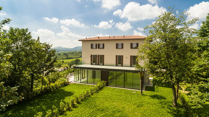 Modern house, two floors, brick facade, large glass windows, red roof, balcony