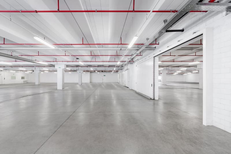 Wide open garage space with concrete floor, white walls, and metal red supports.