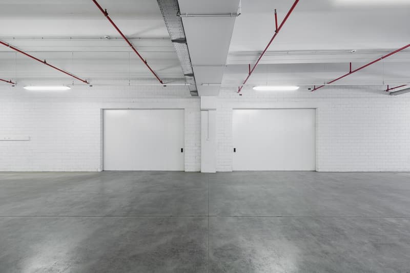 two parking spaces, white brick walls, red overhead pipes, bright fluorescent lights