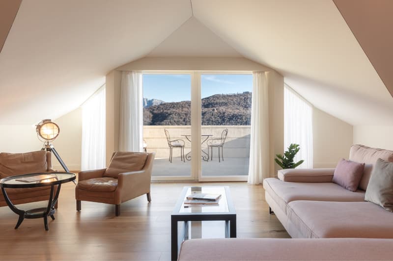 modern living room with balcony, wood floors, pink sofa, brown chairs, coffee table, view of mountains