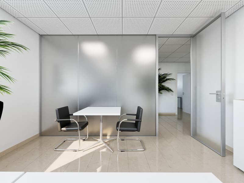 The image shows a modern and minimalist office space with a white table and two black chairs in the center. The walls are made of glass panels, providing a sense of openness and transparency. The ceiling is a grid-like pattern of perforated panels, creati