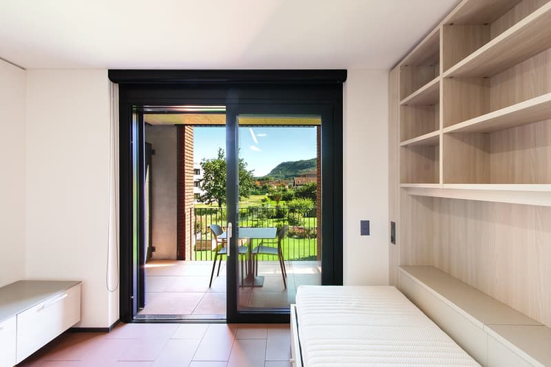 white walls, balcony with table and chairs, sliding glass door, built-in shelf, daybed