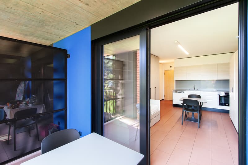 Open-plan living area with dining table, sliding glass doors leading to a balcony or terrace, modern kitchen with white cabinets and appliances
