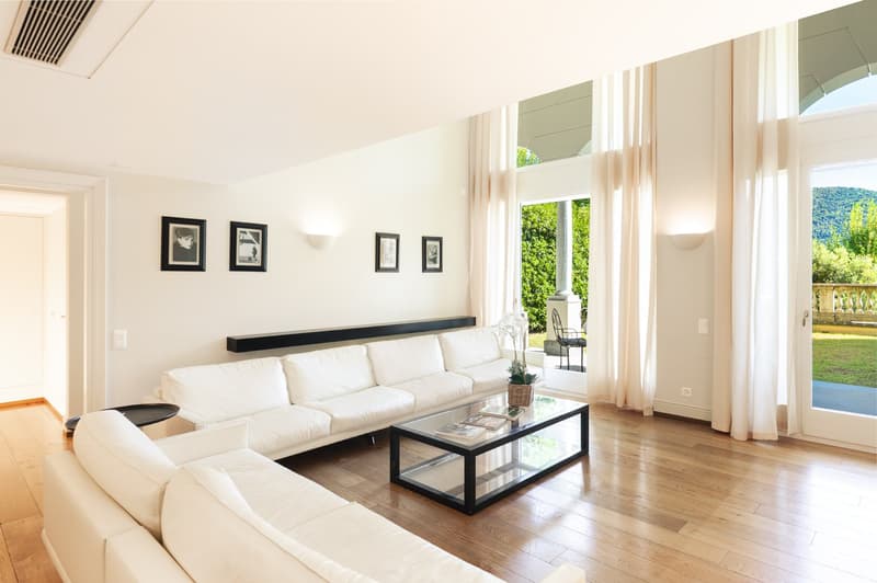 white couches, glass coffee table, sliding glass doors, wooden floor, framed pictures