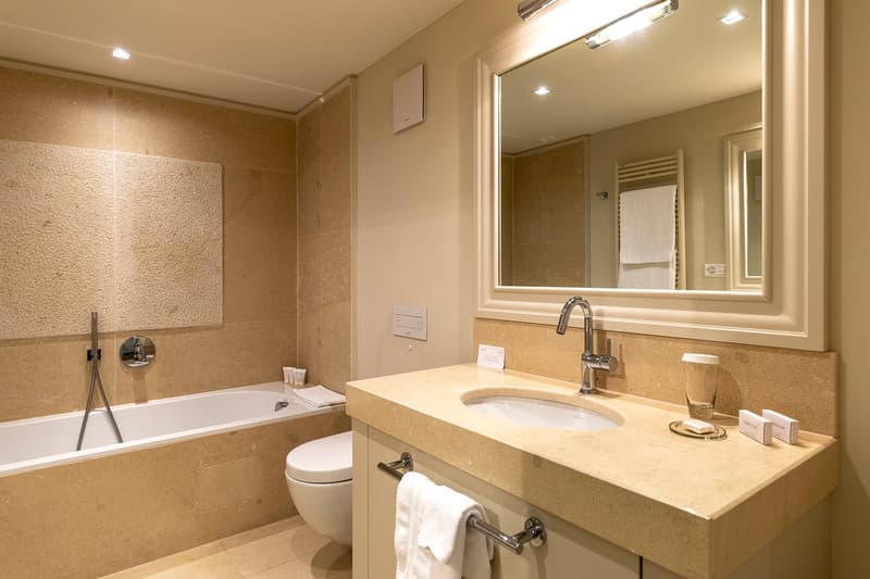 bathroom with bathtub, toilet, sink, mirror and towel racks