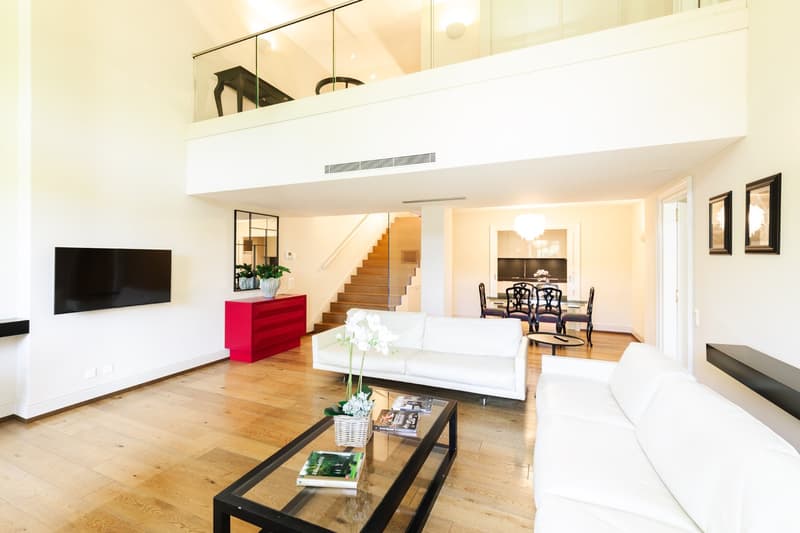 modern style living room, wooden floor, white couch, glass coffee table, balcony, staircase, television, glass wall