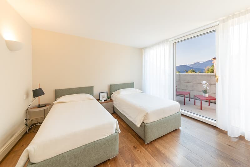 two beds, nightstands, lamps, sliding glass door to balcony, wooden floors, curtains, scenic mountain view