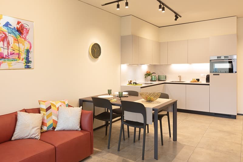 modern kitchen, dining table, seating area with a couch, white cabinetry, floor lamp, decorative art on wall
