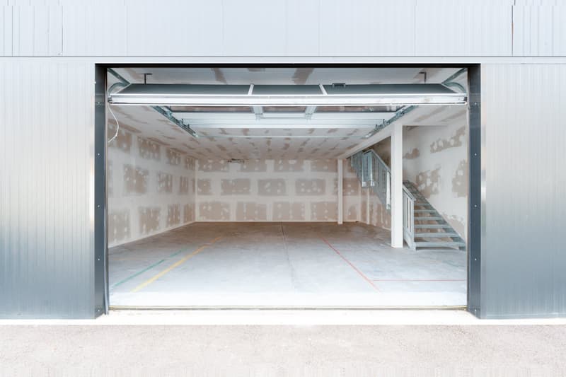 Empty garage with concrete floor, metal ceiling, and a staircase on the right side.