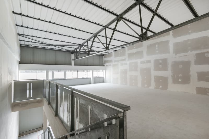 Empty room with white walls, metal ceiling, and glass railings on the stairs