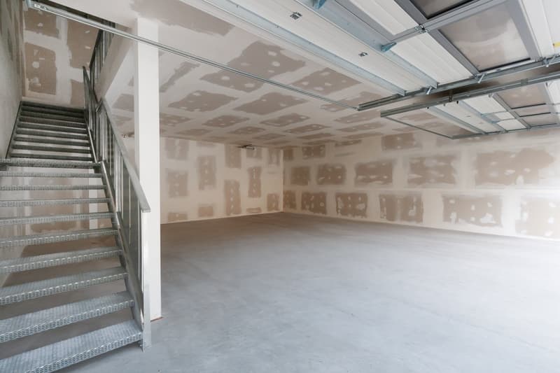 Empty garage with unfinished walls and ceiling, metal staircase