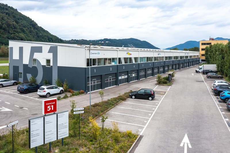 Industrial building with multiple units, large parking lot, multiple cars parked, sign indicating unit 51
