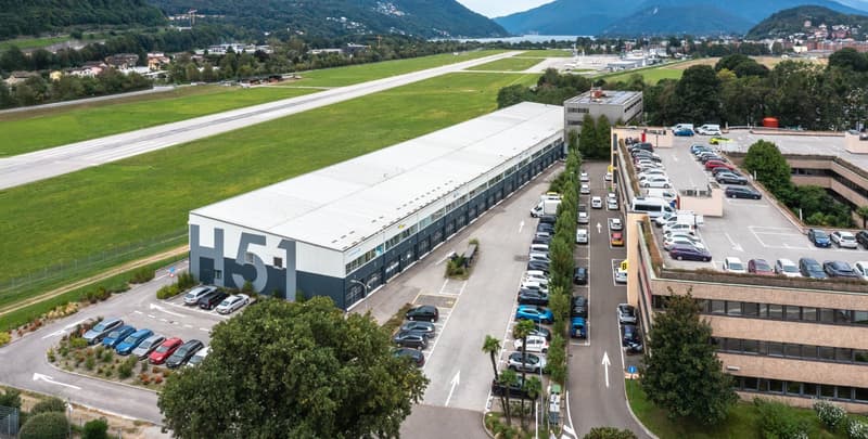 Industrial building with large parking lot, runway in the background