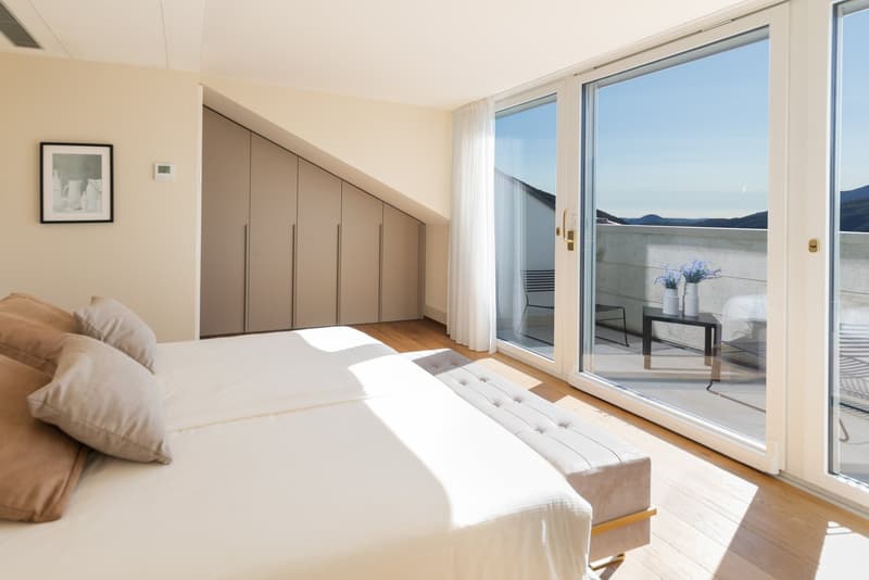 double bed, white linen, 4 pillows, white bench, sliding glass doors, balcony, built-in wardrobes, picture frame