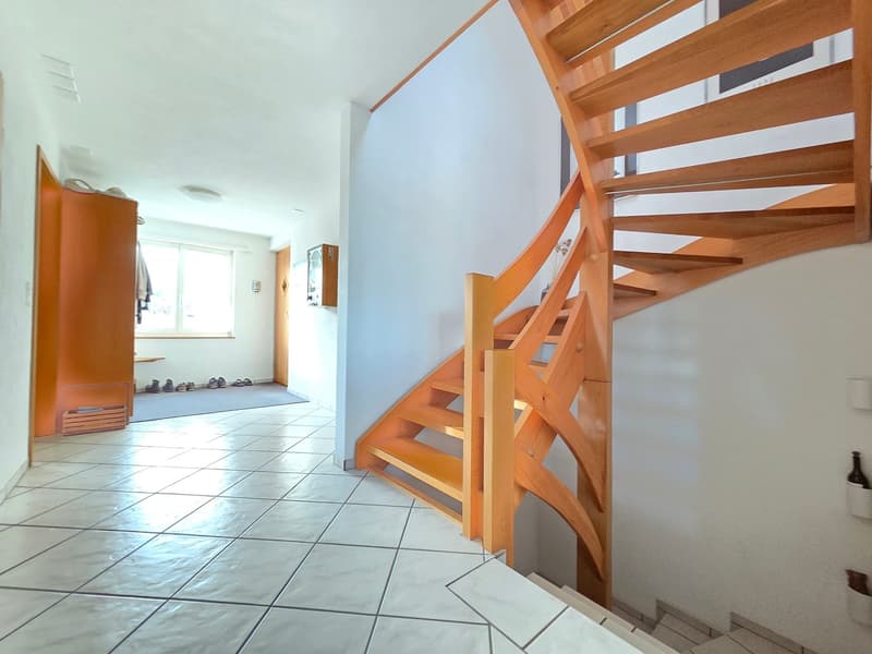 tiled floor, wooden staircase, white walls, door with clothes hanging, shoe rack