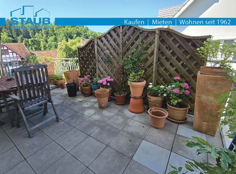 large wooden lattice fence, terrace with tiles, multiple potted plants, wooden chair, small wooden table