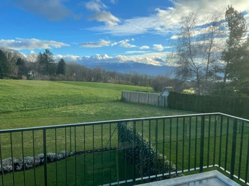 green lawn, bushes, metal fence, mountains in the distance