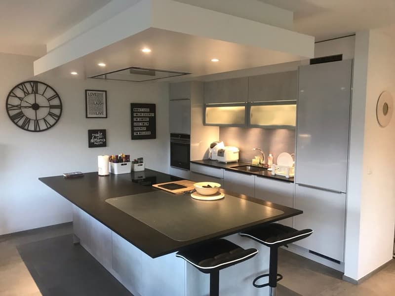 modern kitchen, island countertop, black countertops, white cabinetry, white appliances, wall clocks, light ceiling