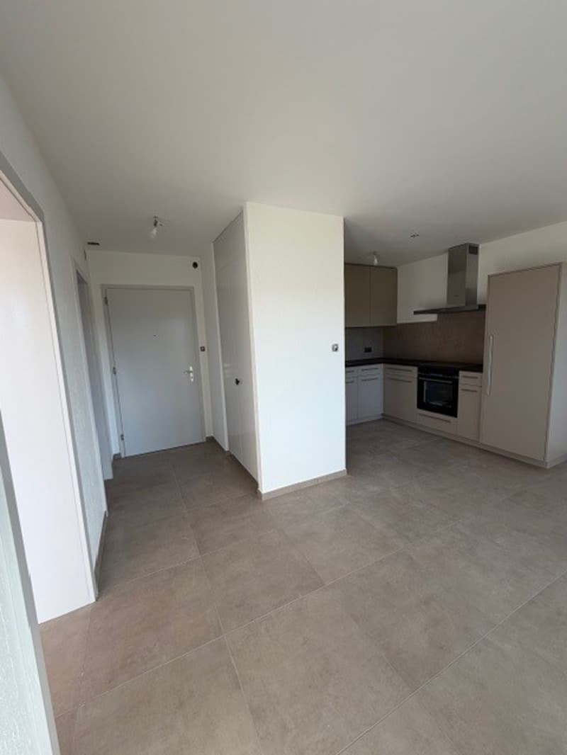 white walls, tile flooring, built-in kitchen with cabinets and counter top, modern appliances, open floor plan