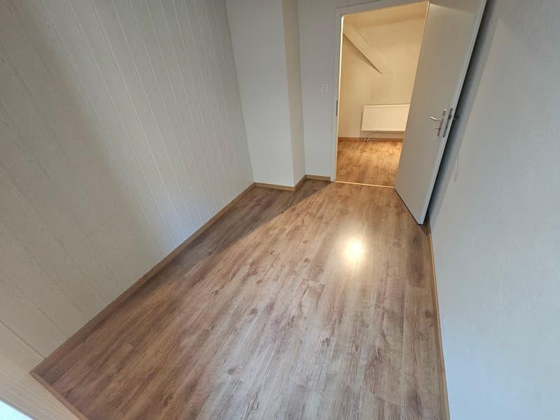 empty room, wooden floor, white walls, open door, light coming from the other room