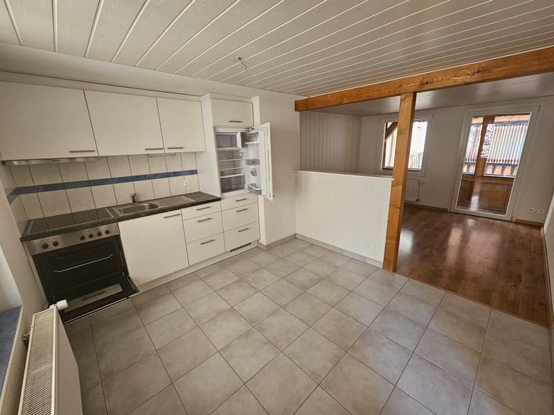 modern kitchen with white cabinets, tiled floor, open refrigerator, gas stove, sink, wooden floor in the hallway