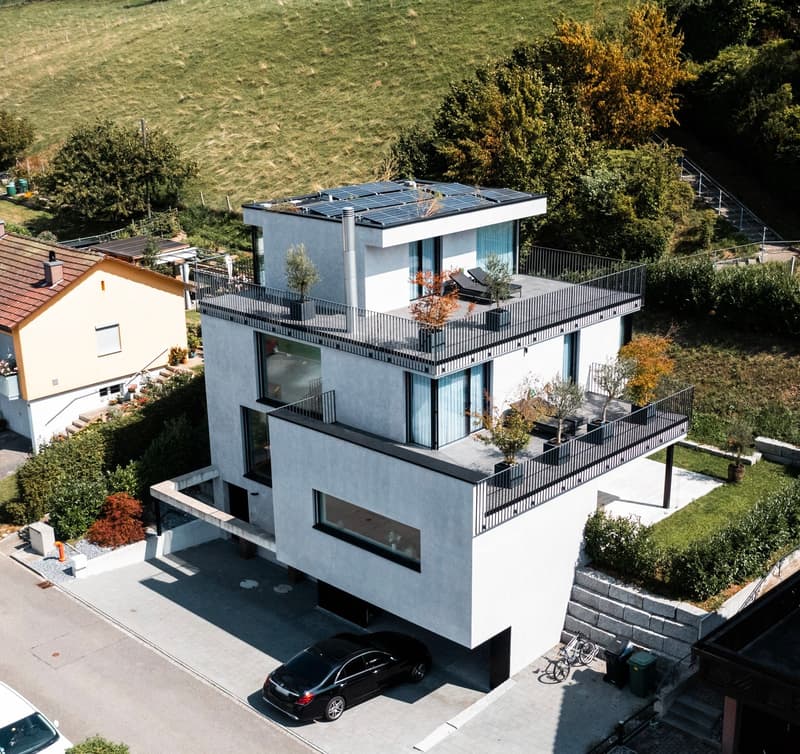 modern design, white exterior, 2 balconies, solar panels on roof, car in driveway