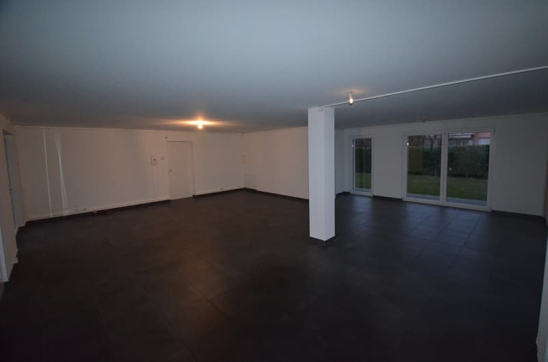 Spacious room with dark tiles, white walls, 2 doors, 2 glass doors, white pillar, natural light