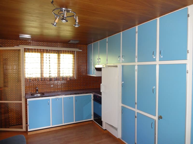 wooden ceiling, blue cabinetry, white fridge, black and silver appliances, tiled wall