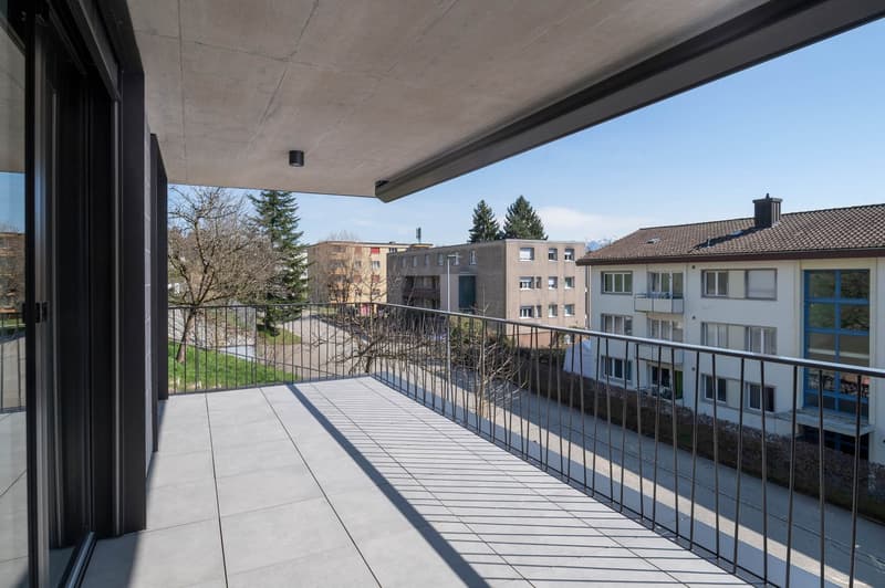 Balcony with tiled floor, metal railing, and a view of the street and buildings