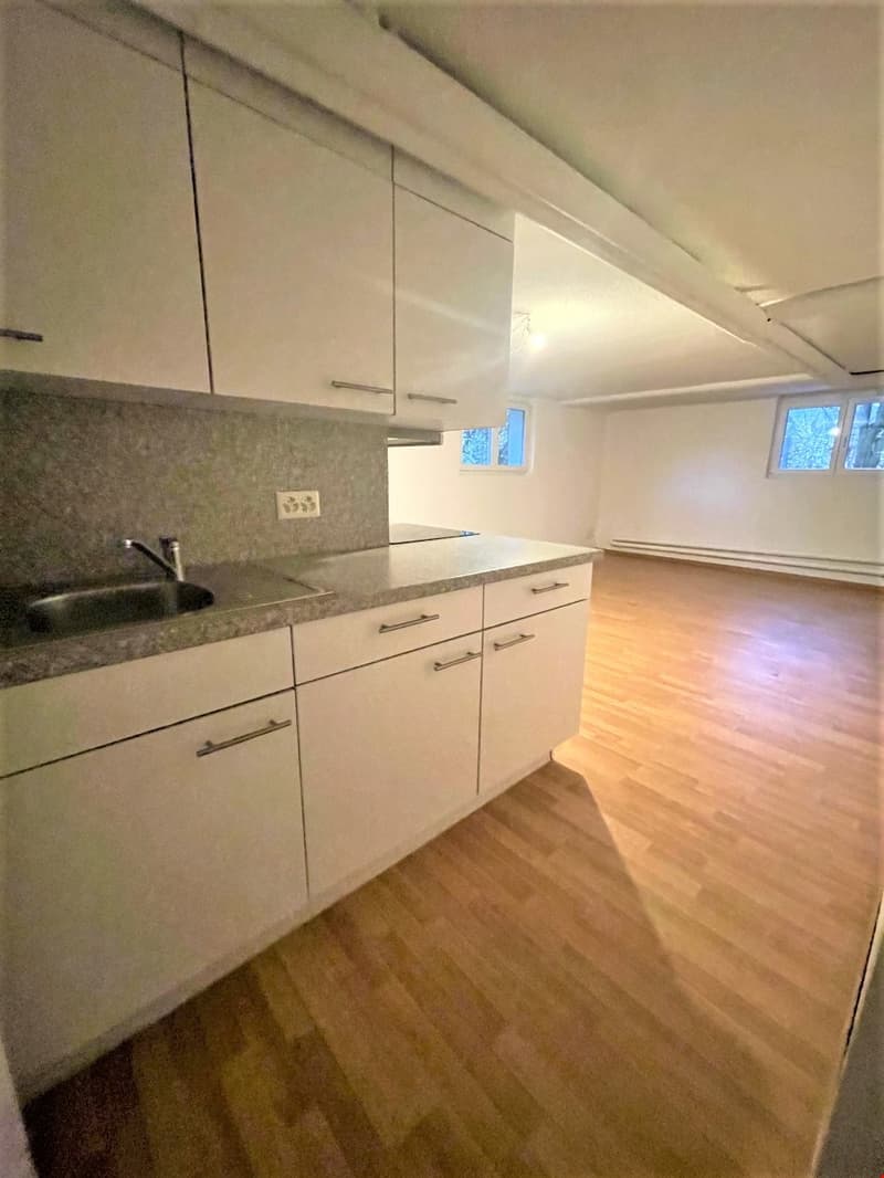 Kitchen with wooden floor, white cabinets, granite countertop, sink with faucet, and windows.