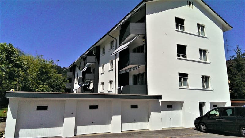 White apartment building with balconies and garage