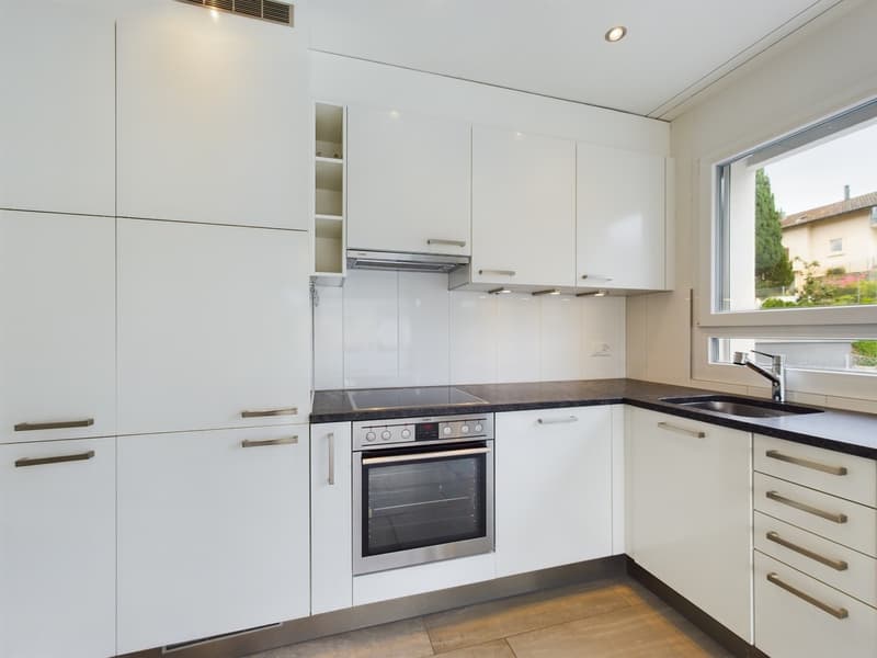 modern kitchen with white cabinets, black countertops, stainless steel appliances, window with view