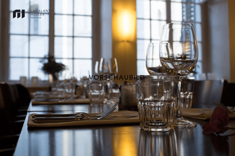 Dining table with wine glasses, water glasses, cutlery, and a flower on the table
