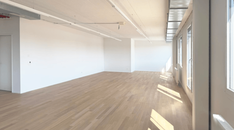 empty room, hardwood floor, white walls, high ceiling, windows with bright sunlight
