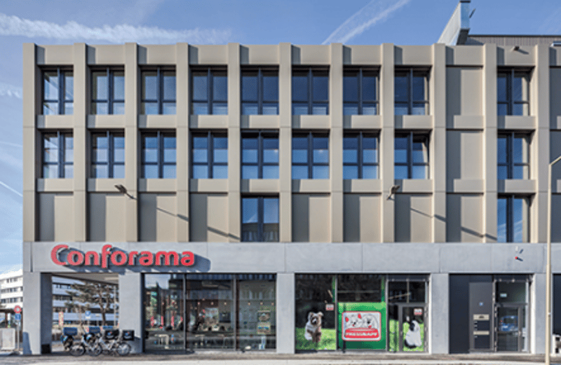 5 story office building, large glass windows, beige wall panels, glass entrance with signage, bicycles parked outside