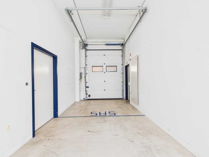 Empty storage room with concrete floor, white walls, blue trims on doors, two doors on left, two doors on right