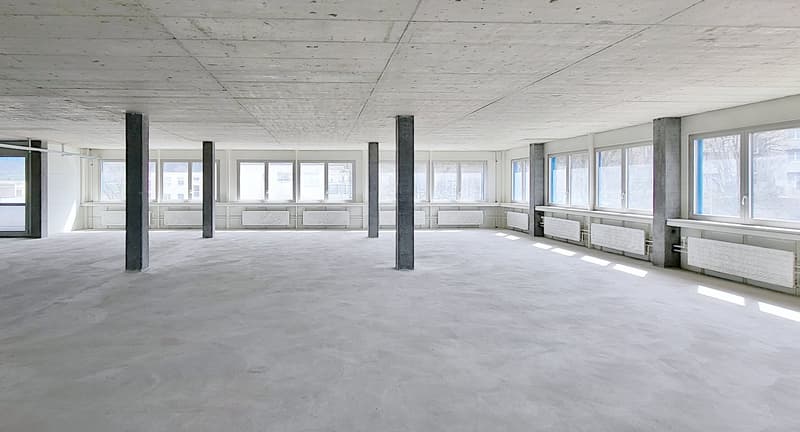 Large empty room, white ceiling, concrete flooring, tall windows, white radiators