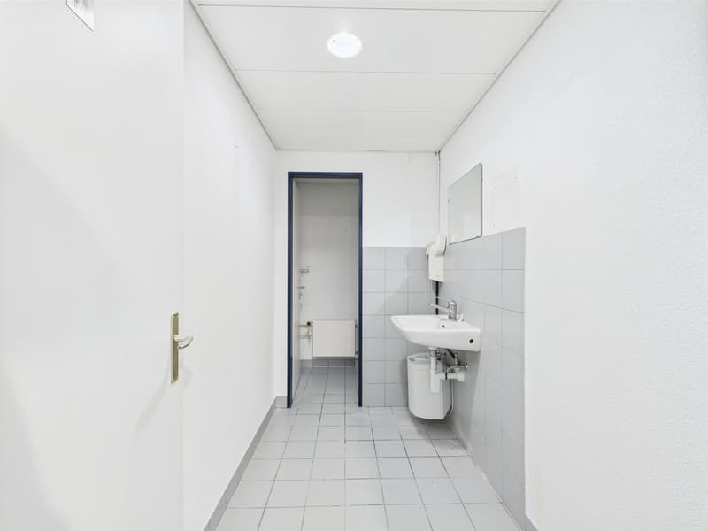 Empty room with a sink, mirror, toilet and radiator