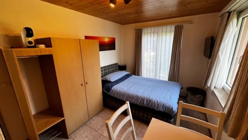 Bedroom with wooden ceiling, wardrobe, bed, and chair