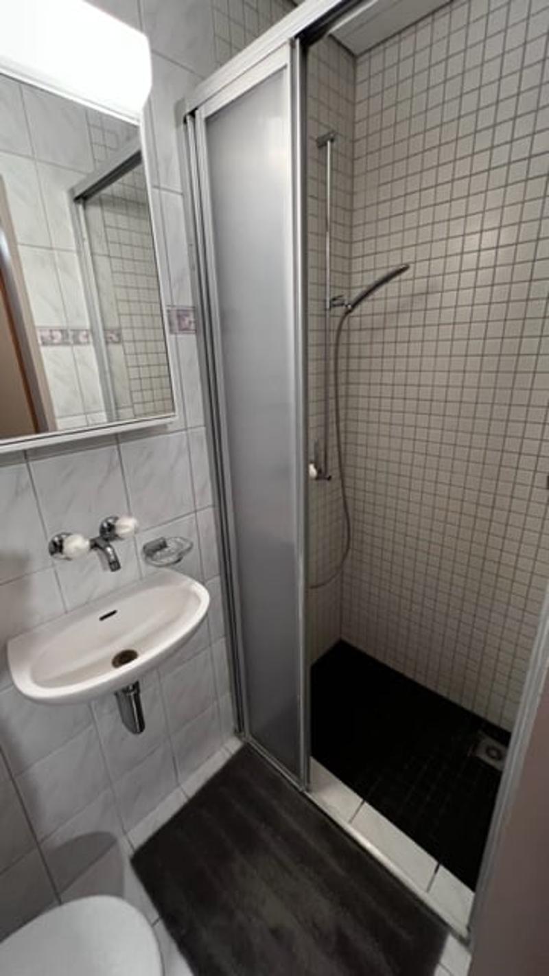 Tiled bathroom with a shower stall, sink, and tile flooring.