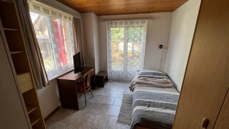 Bedroom with tile flooring, wooden ceiling, large windows, two twin beds, dresser, and access to a balcony or terrace.