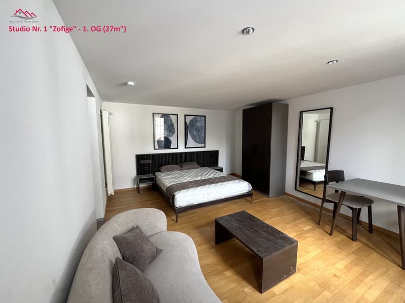 studio apartment with bed, sofa, coffee table, chair, table, mirror, wardrobe