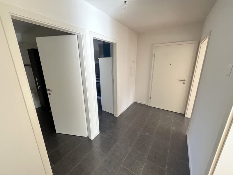 Corridor with tiled floor, white walls, three doors